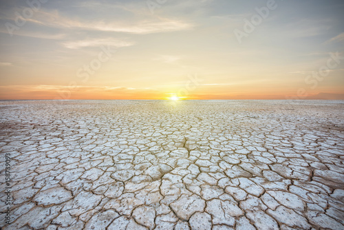 Soil drought cracked landscape on sunset sky
