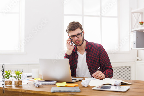 Young concentrated businessman read documents in modern white office