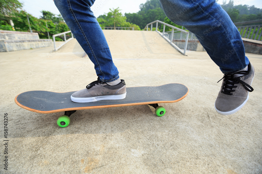 young skateboarder legs riding skateboard at skatepark young skateboarder legs riding skateboard at skatepark