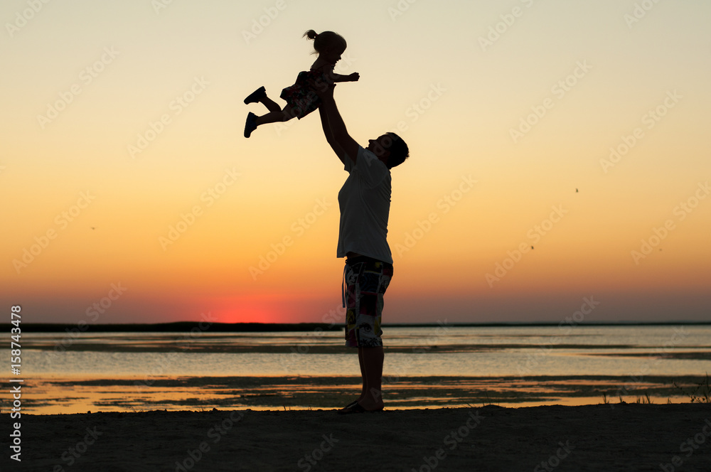 Father and daughter at sunset near the sea