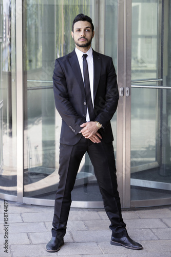 man standing in a suit and tie in front of glass door photo