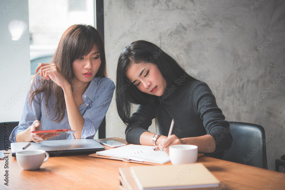 Fototapeta premium Two confused Asian women work on a problem 