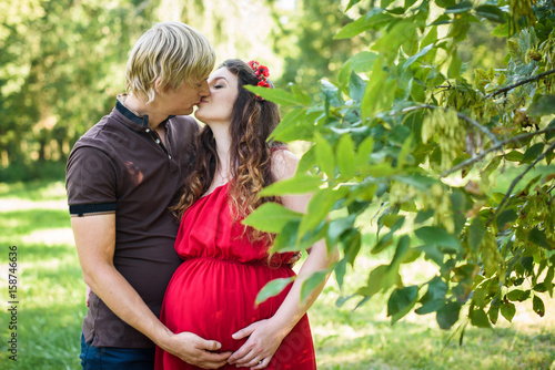 Husband hands on pregnant woman belly  kissing pregnant couple outdoor shooting
