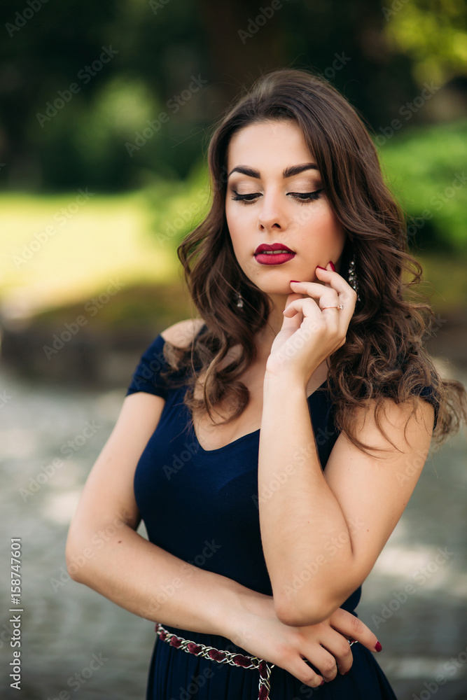 A beautiful girl in a blue dress is walking in the park. Sunny day. Summer. 