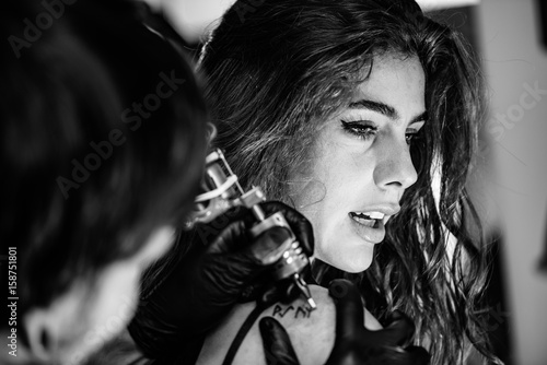 Canvas Print Tattoo artist tattooing young woman