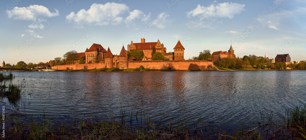 Fototapeta premium Malbork Castle in Poland, medieval fortress of Teutonic Knights Order, view across Nogat River, UNESCO World Heritage Site - panorama 