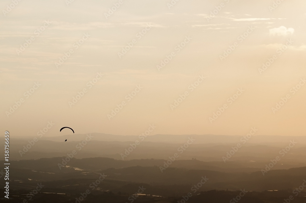 adventure sport - paraglider flying at sunset