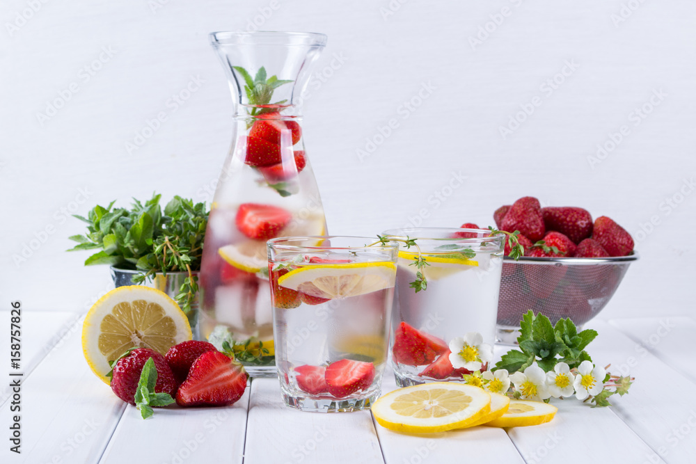 Mineral infused water with strawberry, ice, herb and mint leaves on white background, homemade detox soda water recipe. Mineral infused water with strawberry, ice, herb and mint leaves on white background, homemade detox soda water recipe.