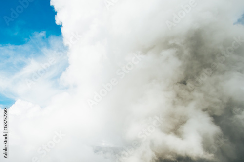 Bromo eruption releasing smoke, steam and ashes to people on the ground. The smoke and blue sky. Steam, smoke and ash fly into the sky very far and cover all the sky with ash, smoke, steam and cloud. 