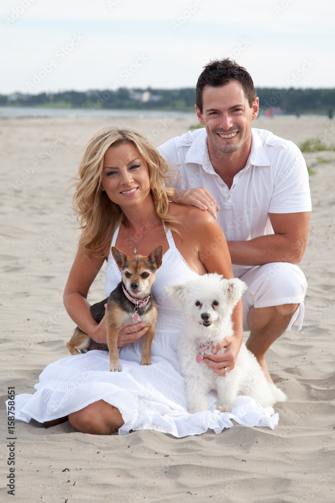 Happy couple relaxing on sandy beach with two cute pet dogs. Happy couple relaxing on sandy beach with two cute pet dogs.