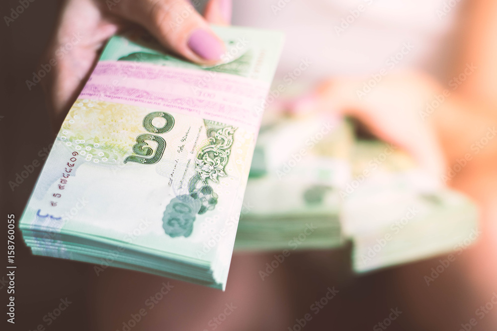 Woman's hand holding Thailand money.