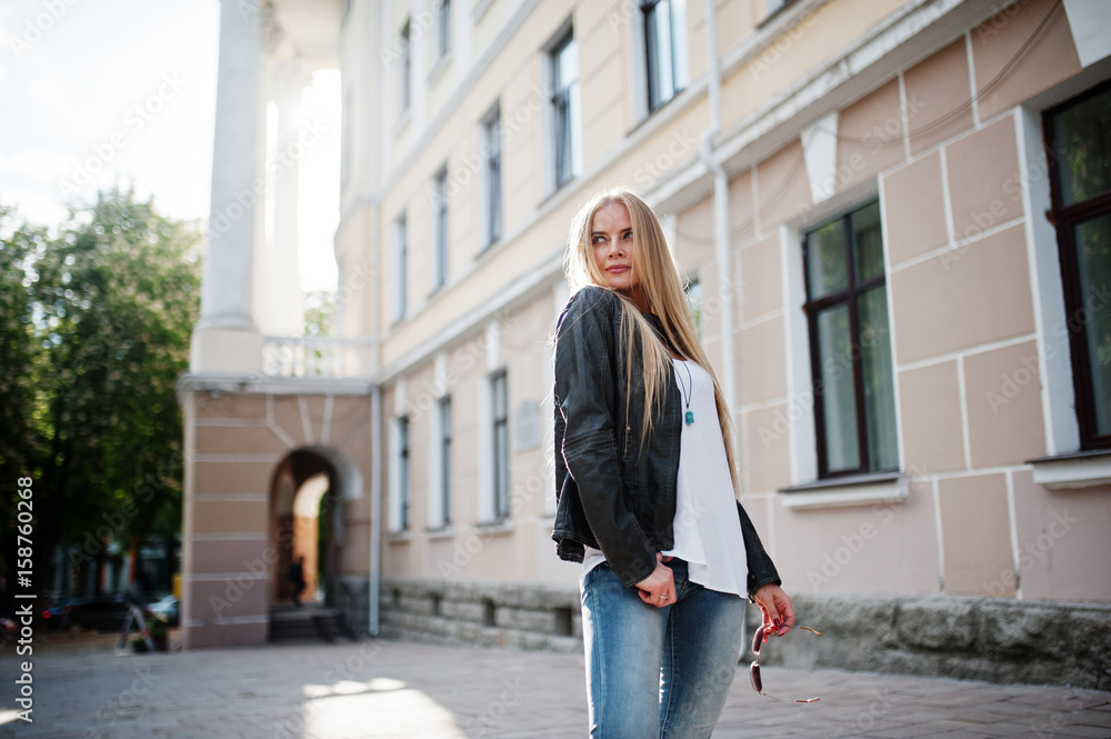 Stylish blonde woman wear at jeans, sunglasses and jacket posed at street on sunshine. Fashion urban model portrait. Stylish blonde woman wear at jeans, sunglasses and jacket posed at street on sunshine. Fashion urban model portrait.