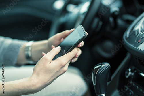 Car driver using smartphone in the car. Phone and hands are in focus.  © BalanceFormCreative