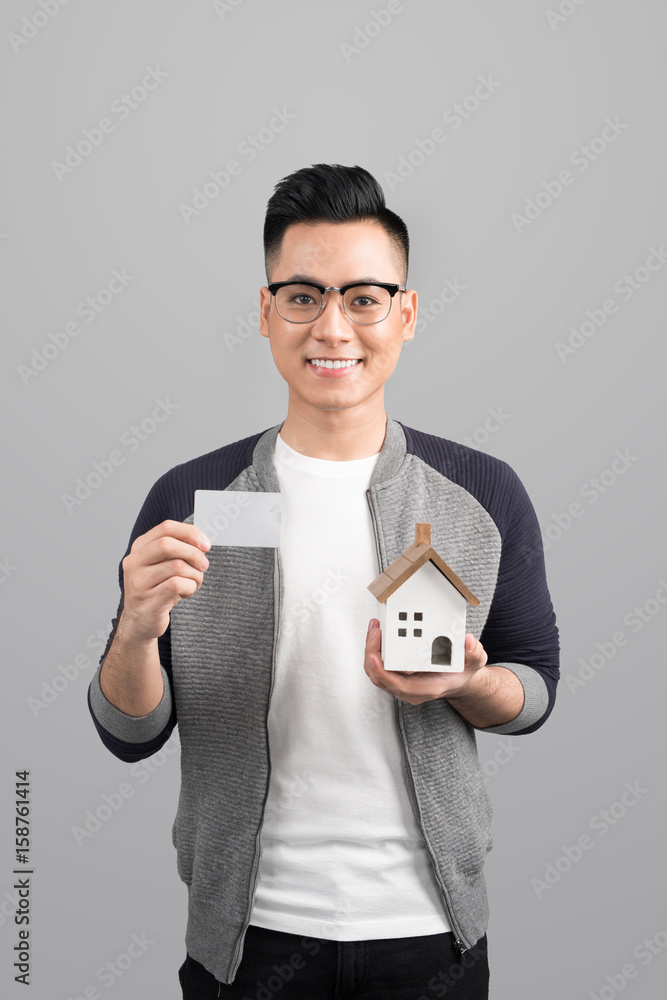 Businessman holding a blank card with an artificial model of the house Businessman holding a blank card with an artificial model of the house