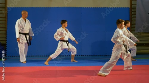 Teenagers martial arts practitioners performing kata at the dojo with sensei karate teacher
