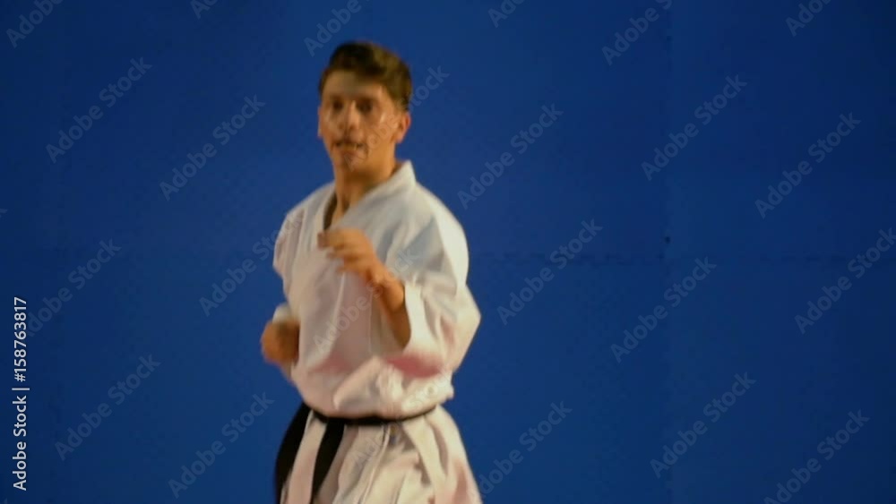 Handsome young black belt karate man exercises punching in slow motion Handsome young black belt karate man exercises punching in slow motion