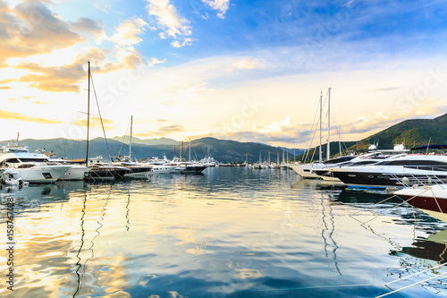 Luxury yachts docked in marina. Port in Mediterranean sea at sunset. Fashionable vacation.