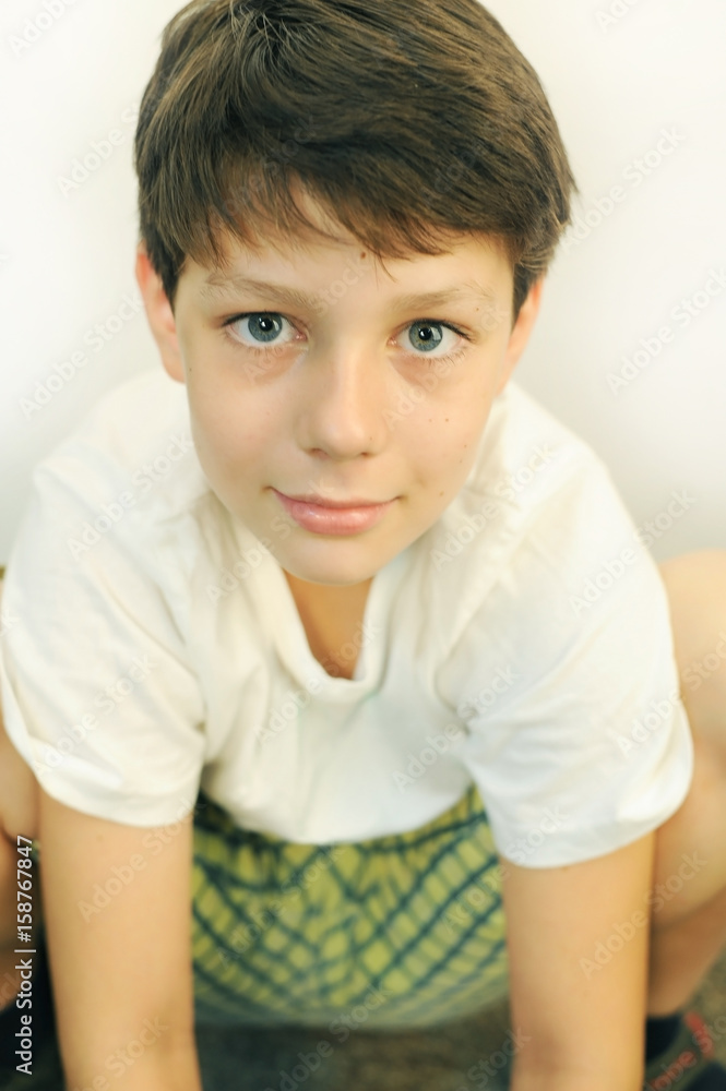 A boy in green shorts and white T-shirt sits and smiles A boy in green shorts and white T-shirt sits and smiles