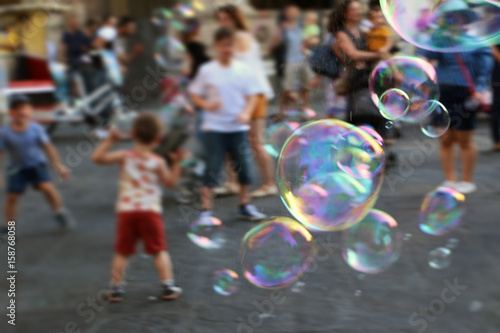  Soap bubbles on the town square and blurry children that are chasing them in the background