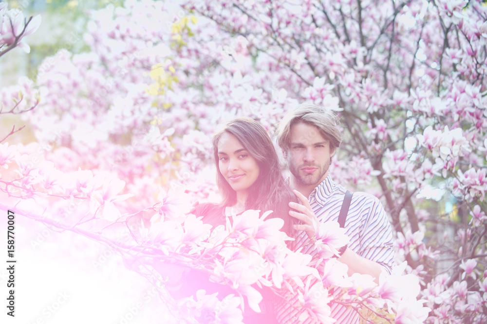 couple in love, man and girl enjoying magnolia flower blossom couple in love, man and girl enjoying magnolia flower blossom