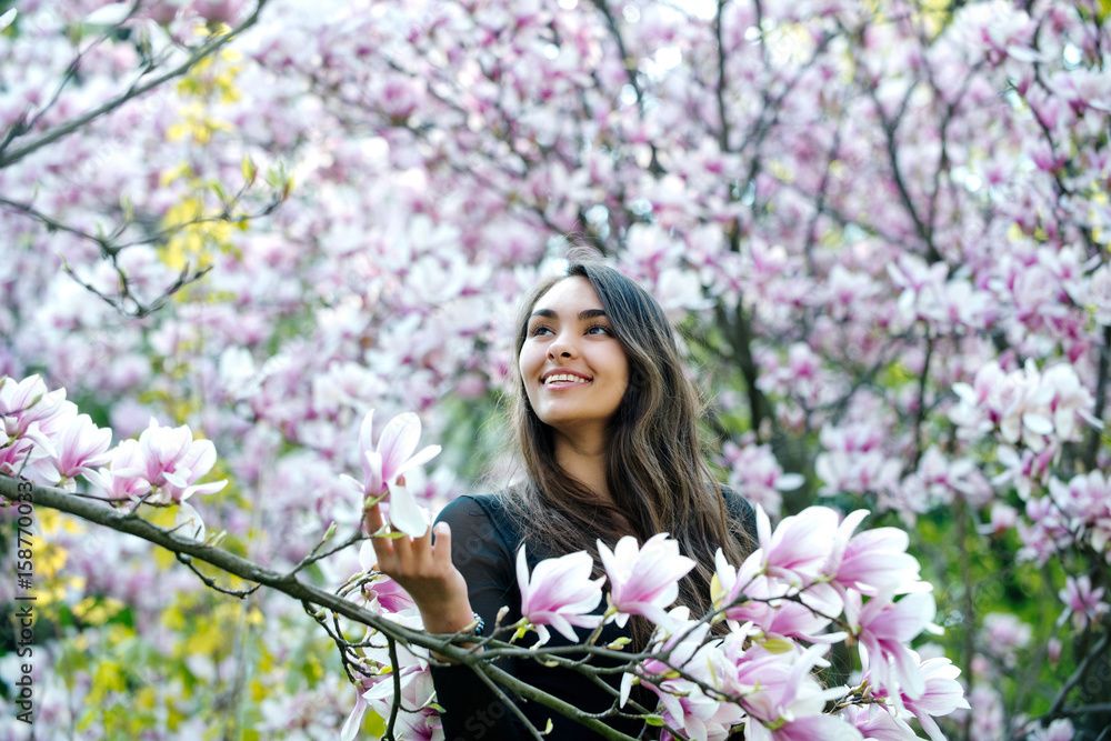 Happy girl smiling at magnolia tree with blossoming flowers Happy girl smiling at magnolia tree with blossoming flowers