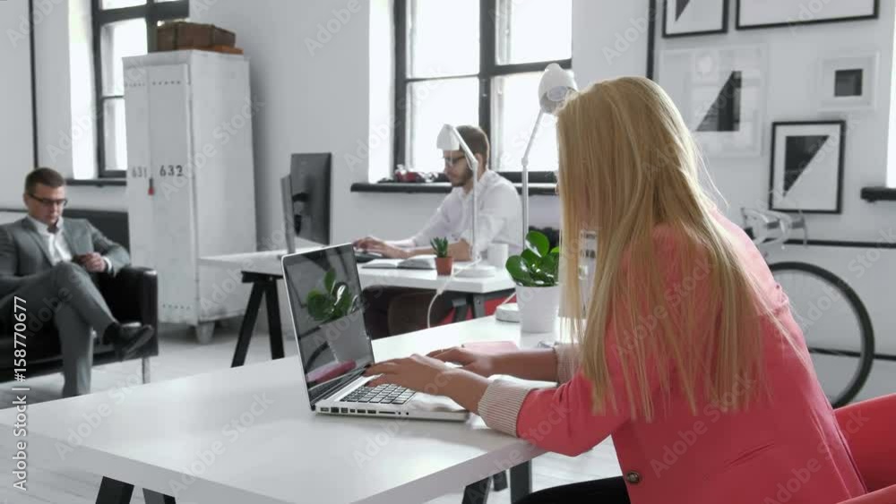 Young business woman working at shared desk in trendy hipster start up office using big data on laptop computer 20s 4k Young business woman working at shared desk in trendy hipster start up office using big data on laptop computer 20s 4k