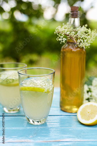 Two glasses of elderflower lemonade and bottle of homemade syrup