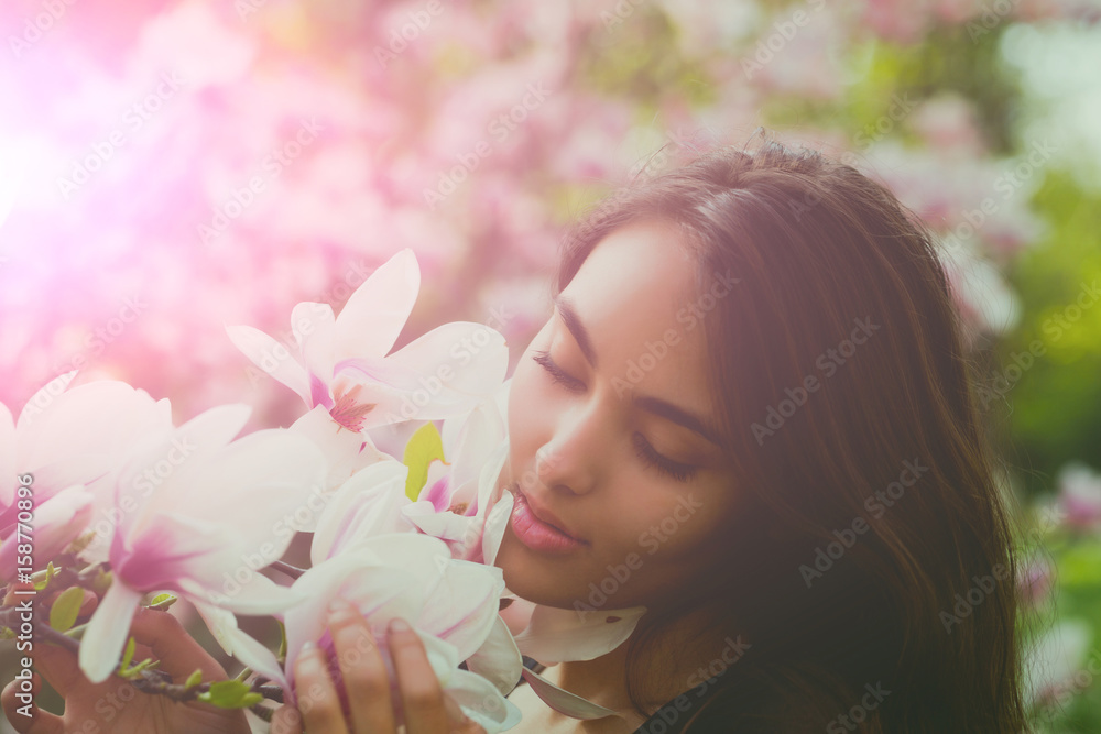Naklejka premium Happy girl with adorable smile smiling at magnolia tree