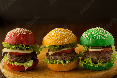 Green, yellow and red burger on wooden table
