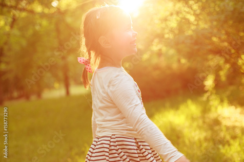 Happy little girl is walking in the park and smiling.child is spinning outdoor 