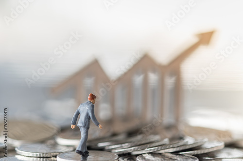 Business and work concept. Businessmen miniature mini figures walking on pile of silever coins and wooden chart icon as background. photo
