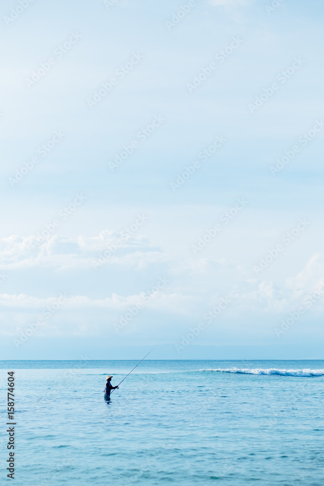 Lonely man fishing by the sea in Bali