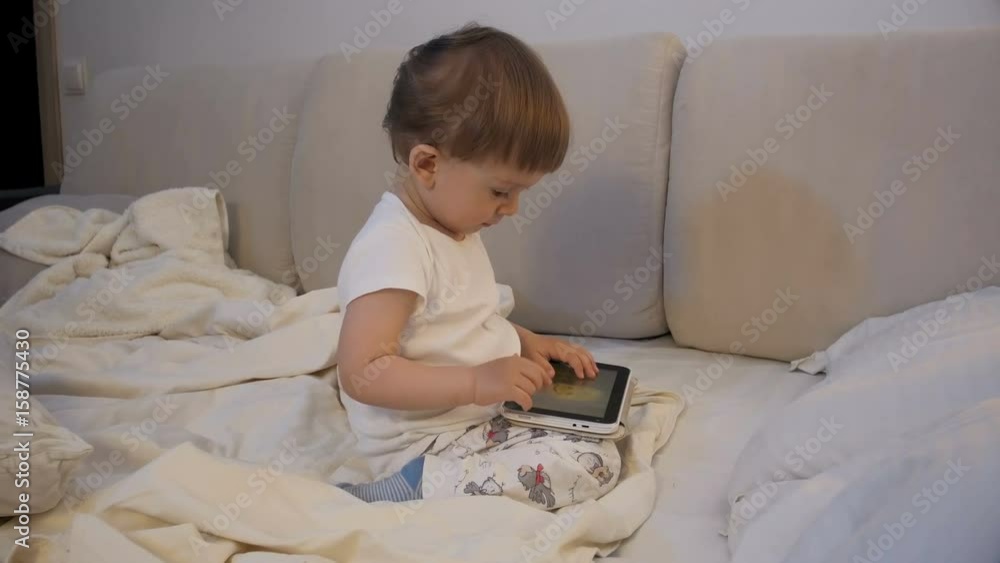 Cute toddler boy using tablet computer in bed before going to sleep Cute toddler boy using tablet computer in bed before going to sleep