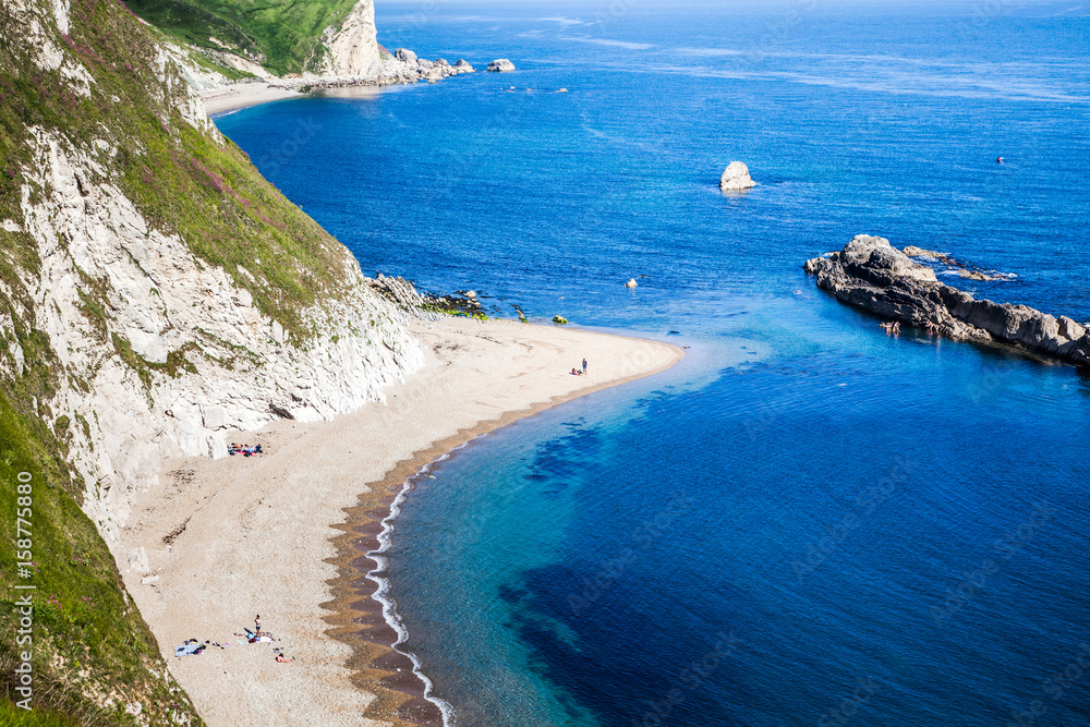 people enjoying a hot summer day on a beautiful hidden beach on the Jurassic Coast of Dorset, UK - Britiish summer holiday destination