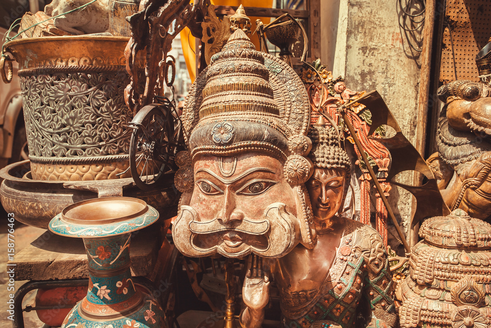 Wooden mask of Indian man with a mustache and vintage artworks of antique store