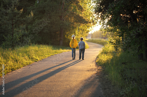 Children stroll along the path in the park on a summer evening. Brother and sister are resting in the fresh air.