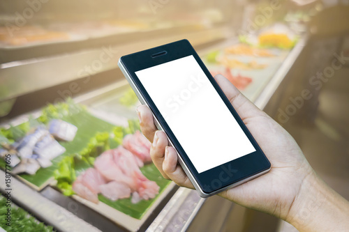 Women ’s Hand holding smart phone with food online device on screen over blur japanese restaurant background, food online, food delivery concept.