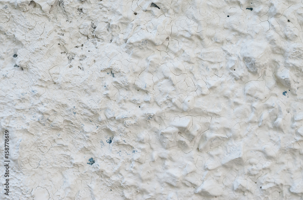 Old white concrete wall with many protruding stones Old white concrete wall with many protruding stones
