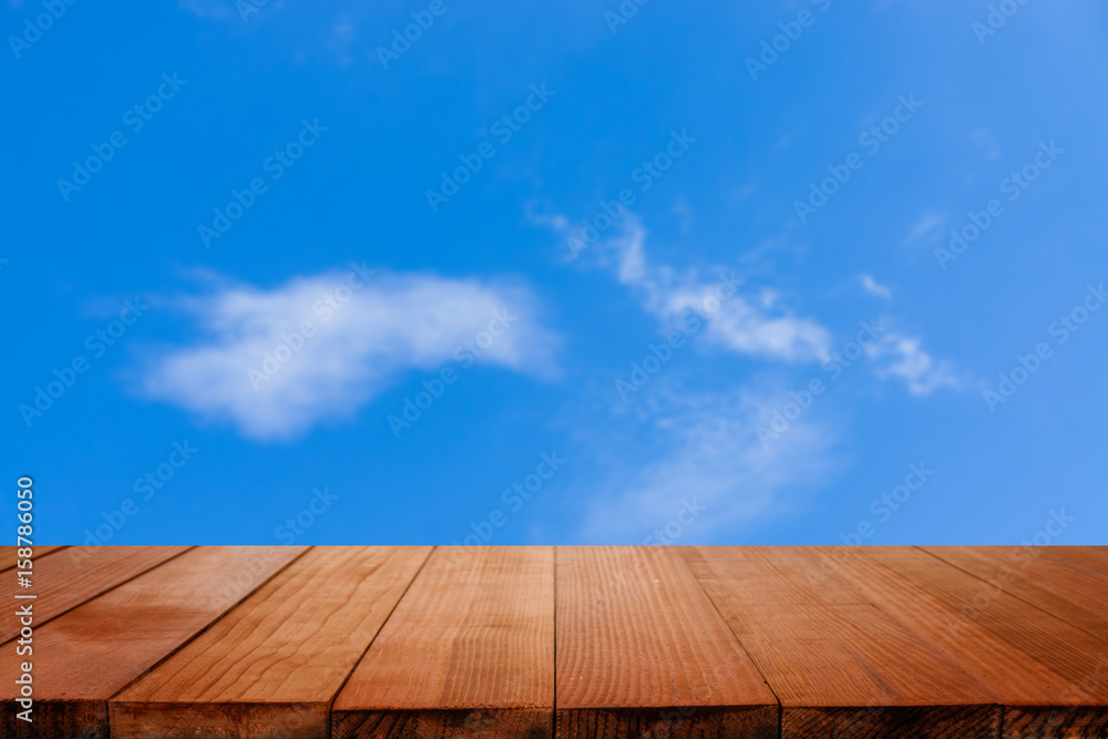 Empty brown wooden table and clouds in the blue sky blur background with bokeh image, for product display montage,can be used for montage or display your products Empty brown wooden table and clouds in the blue sky blur background with bokeh image, for product display montage,can be used for montage or display your products
