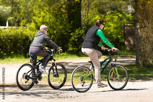 Mother and Son mountain biking on forest trail, back and side view, horizontal