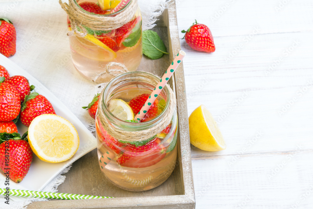 Mineral water with fresh strawberries, lemon and mint in jar on a white wooden background, copy space Mineral water with fresh strawberries, lemon and mint in jar on a white wooden background, copy space