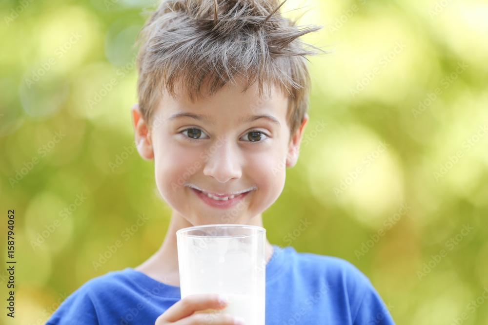 Cute boy in blue shirt holding glass of milk on blurred background Cute boy in blue shirt holding glass of milk on blurred background
