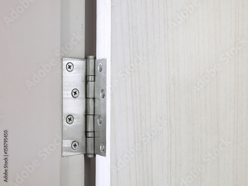 Metal door hinges on white wooden door