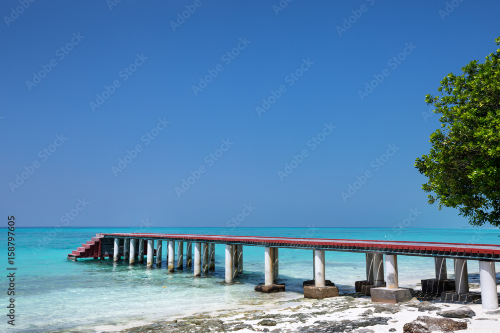 Tropical travel destinations with Maldives island and wooden wharf
