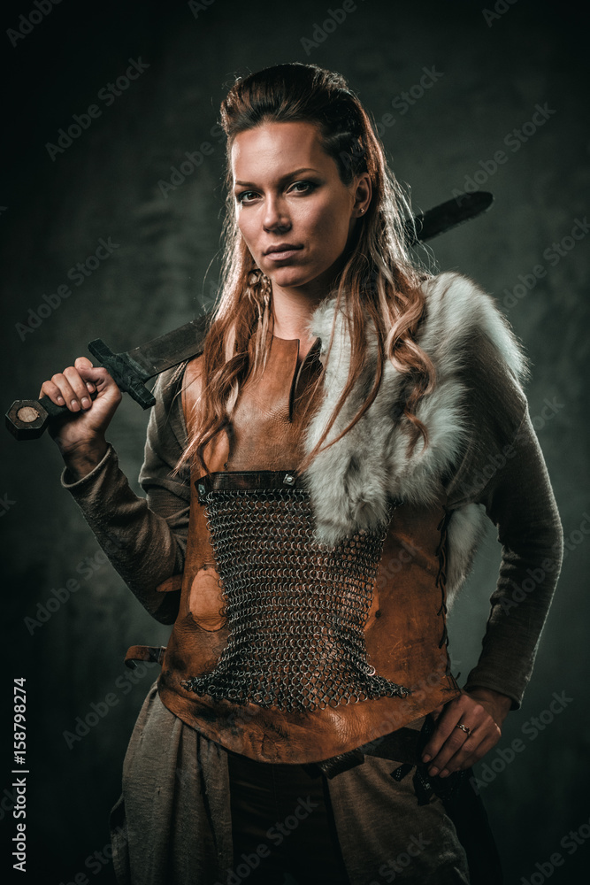 Viking woman with cold weapon in a traditional warrior clothes