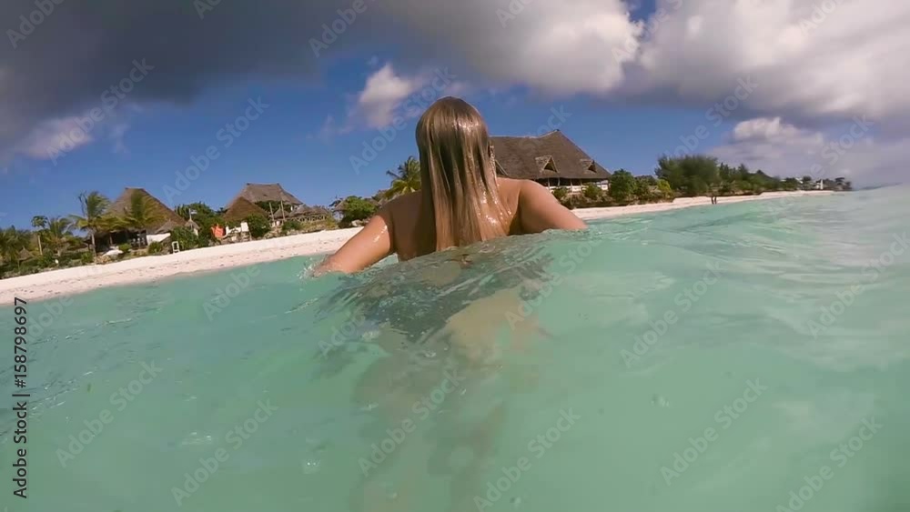The girl emerges from the ocean overlooking a beautiful beach with bungalows and palm trees. Slow motion. The girl emerges from the ocean overlooking a beautiful beach with bungalows and palm trees. Slow motion.