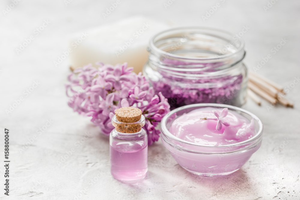 lilac cosmetics with flowers and spa set on stone table background lilac cosmetics with flowers and spa set on stone table background
