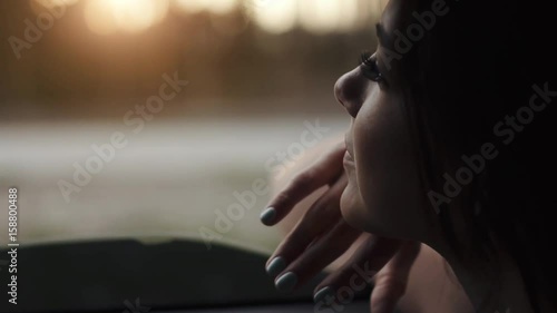 beautiful girl looks out the car window and catches a hand wind