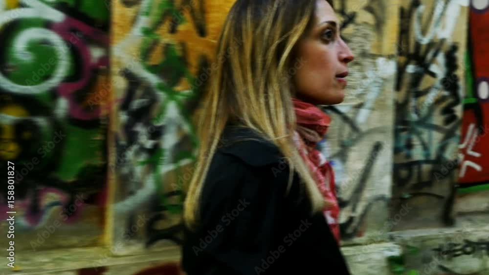 Young curious Woman Walking In The City Alone, looking around- graffiti wall Young curious Woman Walking In The City Alone, looking around- graffiti wall