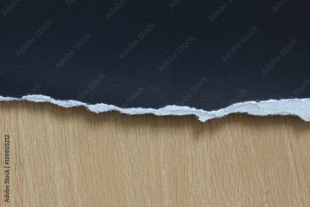 torn black paper on wood background torn black paper on wood background